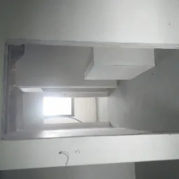 Niedokończona konstrukcja z płyt kartonowo-gipsowych, widoczne profile i fragment okna w tle, surowe wykończenie wnętrza.