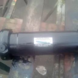 Czarny, odnowiony cylinder hydrauliczny z naklejoną etykietą producenta leżący na drewnianej palecie.