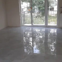 Świeżo położone, połyskliwe płytki podłogowe w pustym pokoju w Jeleniej Górze, z widocznym grzejnikiem owiniętym folią ochronną i balkonem w tle.