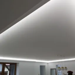 Nowoczesne oświetlenie sufitowe LED z ukrytymi listwami, minimalistyczny design wnętrza z trzema kulistymi lampami wiszącymi.
