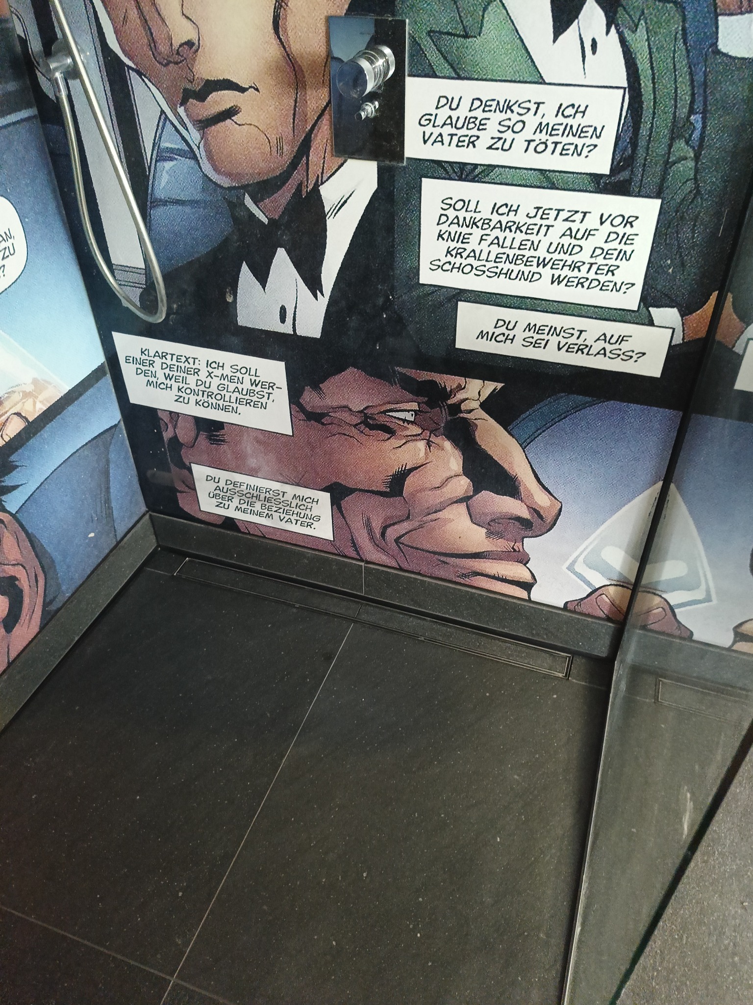 Fragment komiksu w niemieckiej wersji językowej, przedstawiający dialog postaci z widocznymi dymkami z tekstem. Kadry komiksu ułożone pod kątem, ukazujące różne ujęcia twarzy i sylwetek bohaterów.