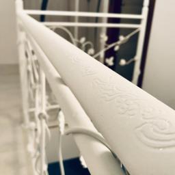 Errementari Adrian Leśniak - Biała, metalowa balustrada schodowa z delikatnym wytłaczanym wzorem, widok z góry, oświetlenie dzienne.