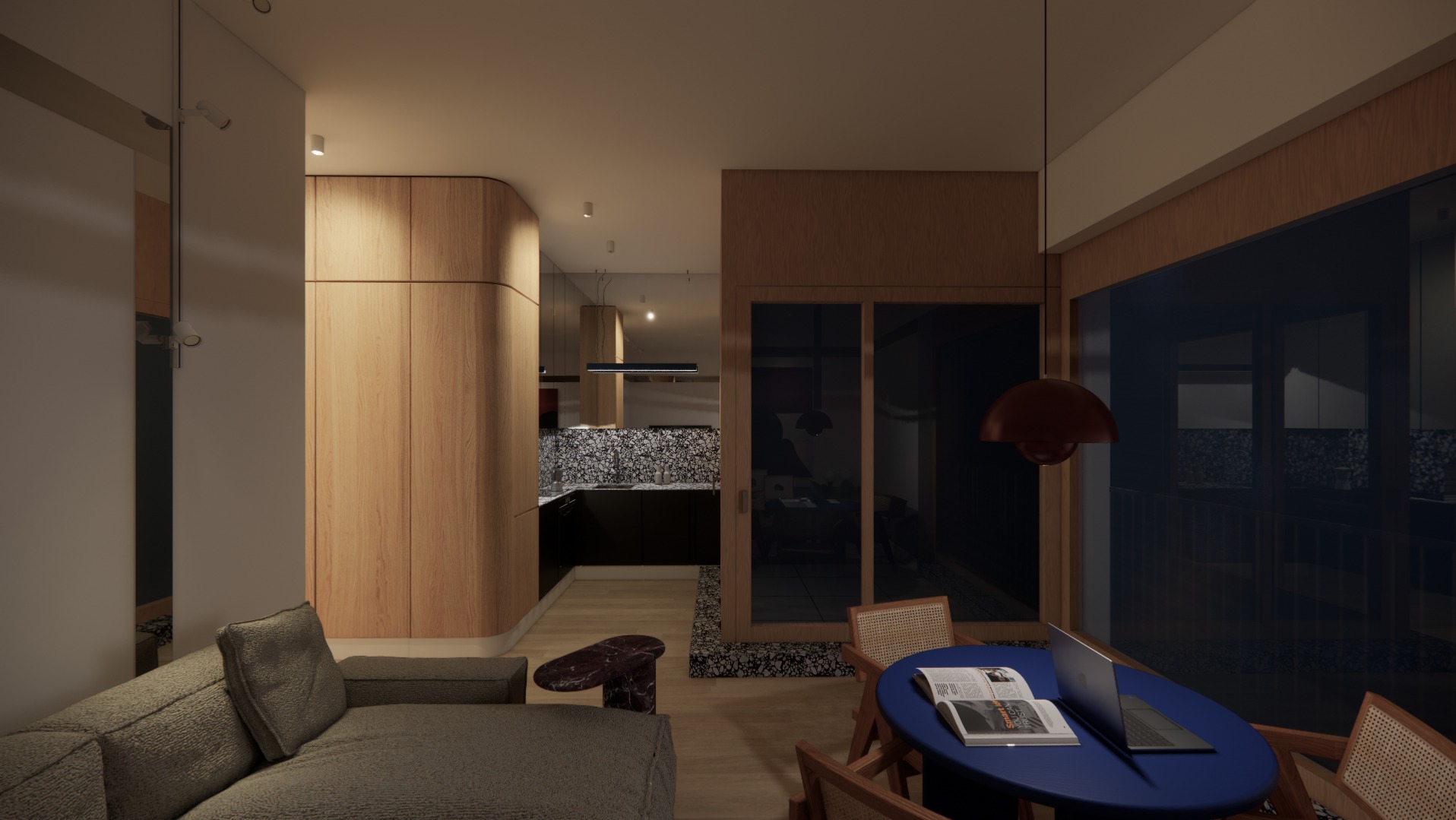 Wnętrze mieszkania z drewnianą zabudową, sofą i okrągłym stołem z laptopem. Widok na kuchnię z czarnymi szafkami i wzorzystą ścianą. Ciepłe oświetlenie.