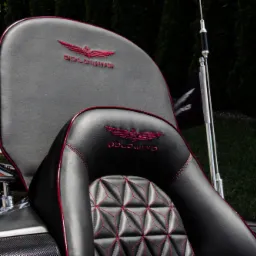 Czarne, skórzane siedzenie motocyklowe z czerwonymi przeszyciami i haftowanym logo Goldwing, zamontowane na motocyklu.