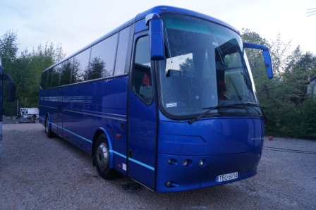 Niebieski autokar turystyczny zaparkowany na żwirowym placu, widok z przodu i boku, z widoczną tablicą rejestracyjną TBU 6V14.