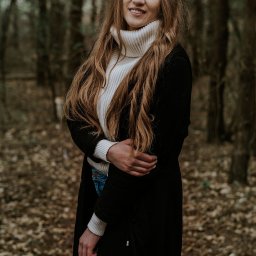 Ulotne chwile- Filipiak fotografia - Portret uśmiechniętej kobiety w białym golfie i czarnym płaszczu na tle jesiennego lasu.