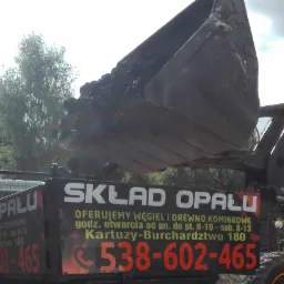 Ładowarka czołowa wysypuje węgiel do skrzyni samochodu ciężarowego z reklamą składu opału w Kartuzach