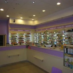 Wnętrze apteki z półkami wypełnionymi lekami, suplementami diety i innymi produktami, oświetlone punktowymi lampami sufitowymi, z ladą w kolorach fioletu i beżu.