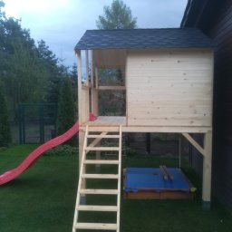 DM PARTNER Dariusz Pietrzak - Drewniany plac zabaw dla dzieci z czerwoną zjeżdżalnią, schodami i zadaszoną piaskownicą, umieszczony w ogrodzie przy drewnianym domu.
