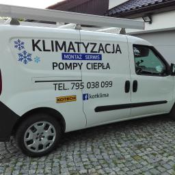KOTECH Paweł Kot - Biały samochód dostawczy z logo firmy świadczącej usługi montażu, serwisu klimatyzacji i pomp ciepła, zaparkowany na kostce brukowej przed garażem.