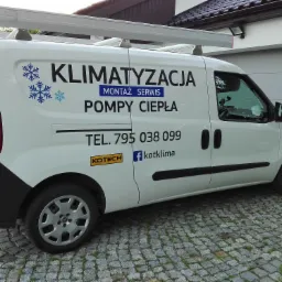Biały samochód dostawczy z logo firmy świadczącej usługi montażu, serwisu klimatyzacji i pomp ciepła, zaparkowany na kostce brukowej przed garażem.