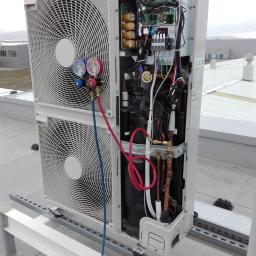 KOTECH Paweł Kot - Serwis klimatyzacji w Dzierżoniowie: klimatyzator z otwartą obudową, podłączone manometry i butla z gazem chłodniczym na dachu budynku przemysłowego.