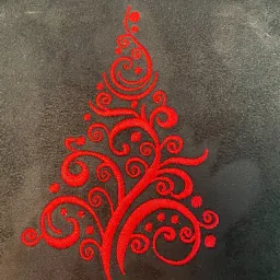 Czerwony, stylizowany motyw choinki, wykonany techniką haftu na ciemnoszarym, pluszowym materiale.