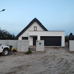 mijabodeSign - Nowoczesny dom jednorodzinny z garażem i elementami ogrodzenia z betonu architektonicznego, widziany z zewnątrz w trakcie budowy. Na pierwszym planie zaparkowany biały Land Rover.