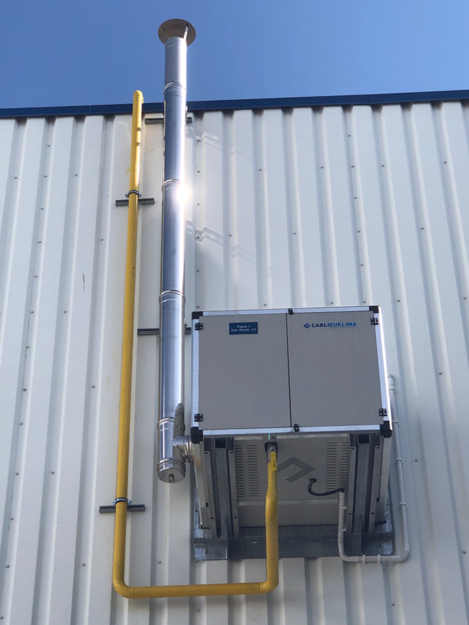 System ogrzewania promiennikami gazowymi z jednostką termiczną zainstalowaną na zewnątrz obiektu.