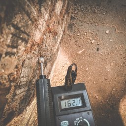 Doradztwo Techniczne Hydromaster - Pomiar wilgotności ściany budynku za pomocą wilgotnościomierza GANN HydroMaster, wskazującego wartość 162.1, w celu diagnostyki problemów z wilgocią.