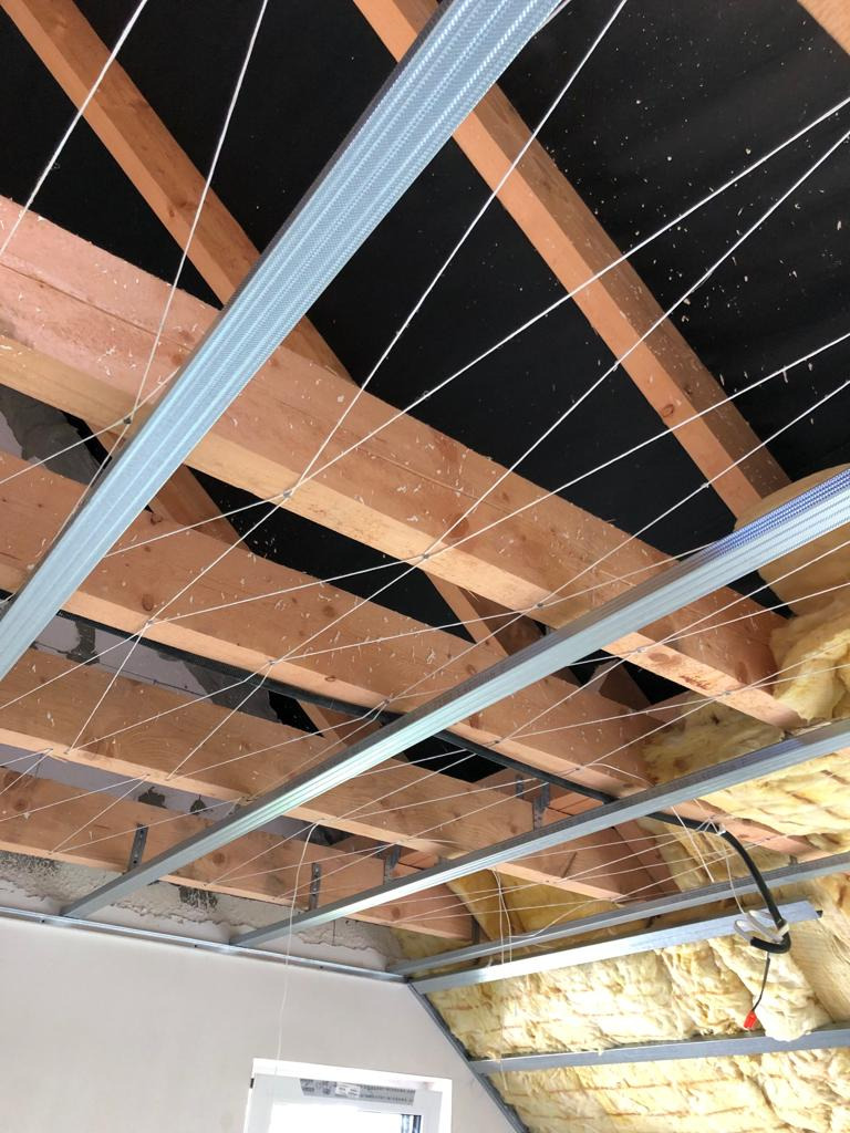 Montaż sufitu podwieszanego z metalowym stelażem i izolacją z wełny mineralnej na poddaszu w Ostrowie Wielkopolskim.