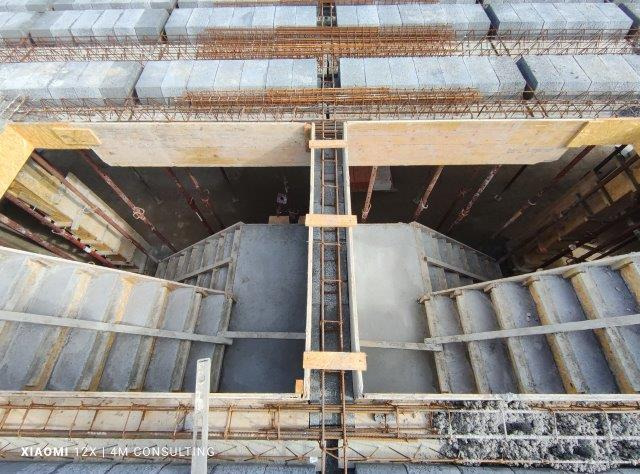 Wnętrze konstrukcji stropu żelbetowego w trakcie budowy, widoczne szalunki, zbrojenie i betonowe bloki stropowe.