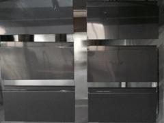 Szare, metalowe elementy balustrady z poziomymi, srebrnymi akcentami, ułożone w rzędach, prawdopodobnie przed montażem.