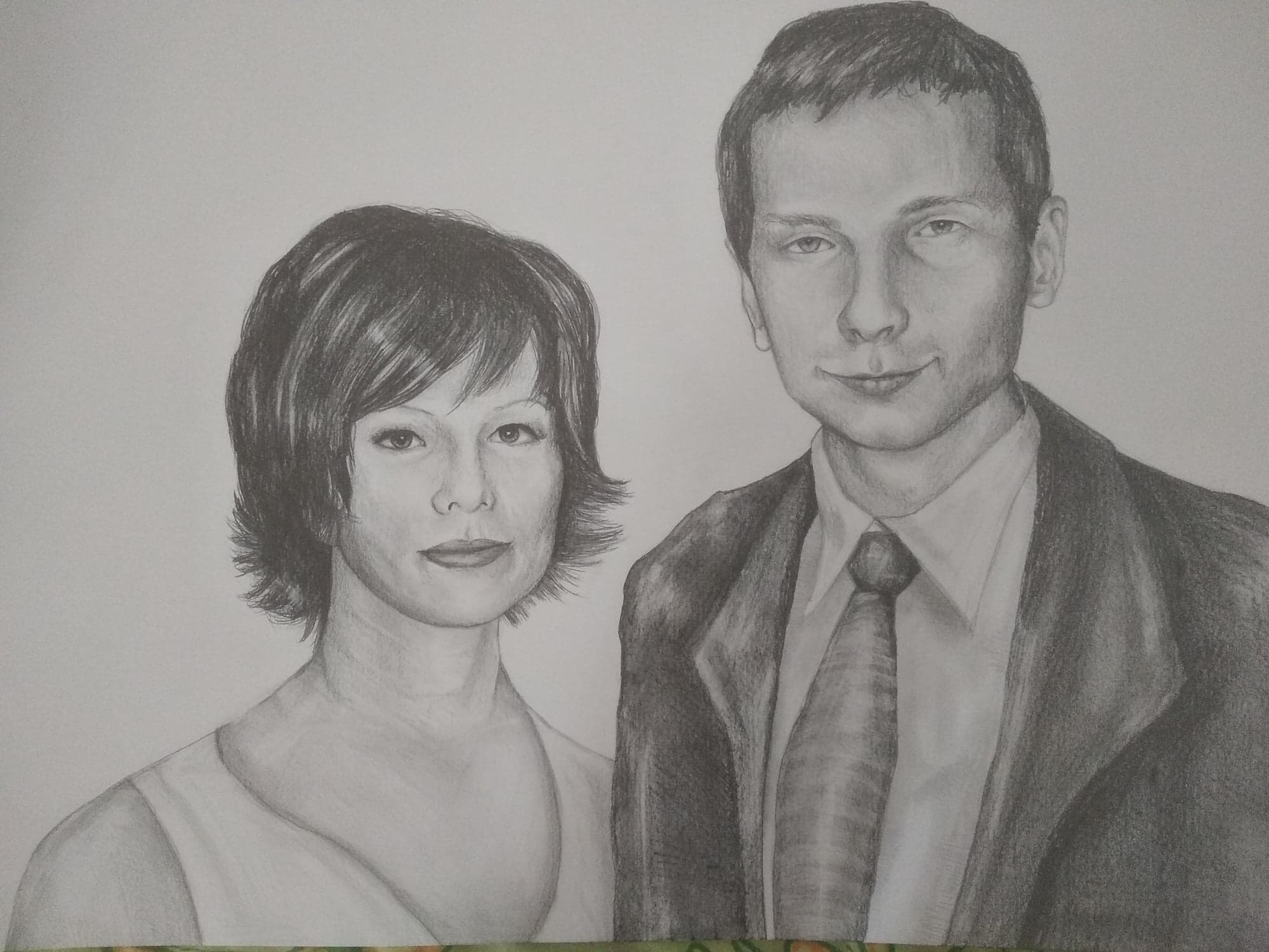 Ręcznie rysowany portret pary: kobieta z krótkimi włosami i mężczyzna w garniturze i krawacie, wykonany ołówkiem na papierze.