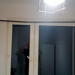 Mirosław Ziemniak - Białe, dwuskrzydłowe drzwi balkonowe z czarną szyną karnisza zamontowaną nad nimi, widoczne w jasnym, minimalistycznym wnętrzu.