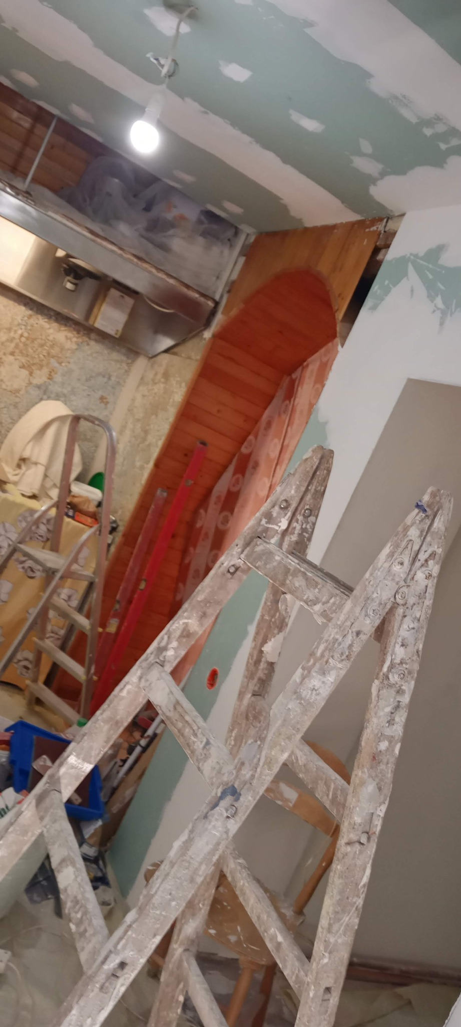 Wnętrze w trakcie remontu: widoczna drewniana drabina, fragment drewnianego sufitu i ściana z nałożoną warstwą szpachli, przygotowywana do dalszych prac wykończeniowych.