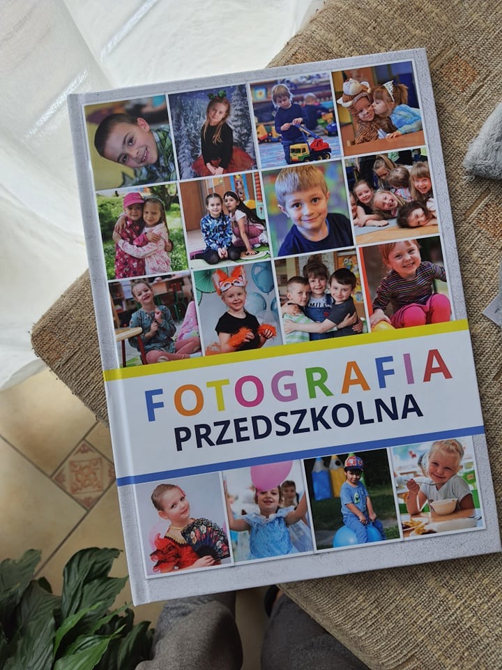 Album fotograficzny z kolażem zdjęć dzieci przedszkolnych na okładce, leżący na beżowym tle.