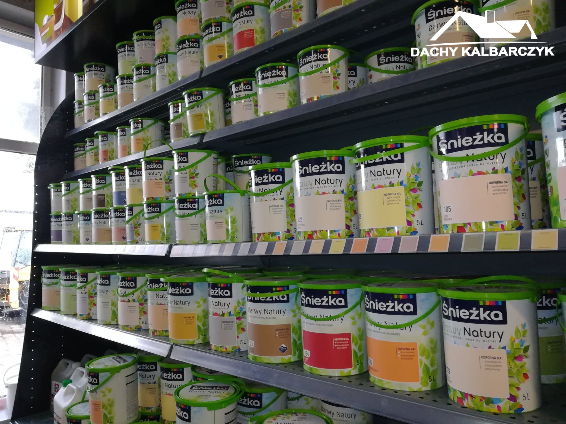 Półki w sklepie z farbami Sniezka Barwy Natury w różnych odcieniach i pojemnościach, widoczne etykiety z informacjami o produkcie.