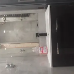 Wnętrze łazienki w trakcie remontu w Sosnowcu: położone szare płytki podłogowe, widoczna instalacja wodna, czarna szafka pod umywalką i butelka z mydłem w płynie.