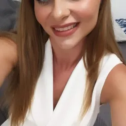 Uśmiechnięta kobieta w białym stroju, prawdopodobnie doradca, prezentuje się profesjonalnie i przyjaźnie.