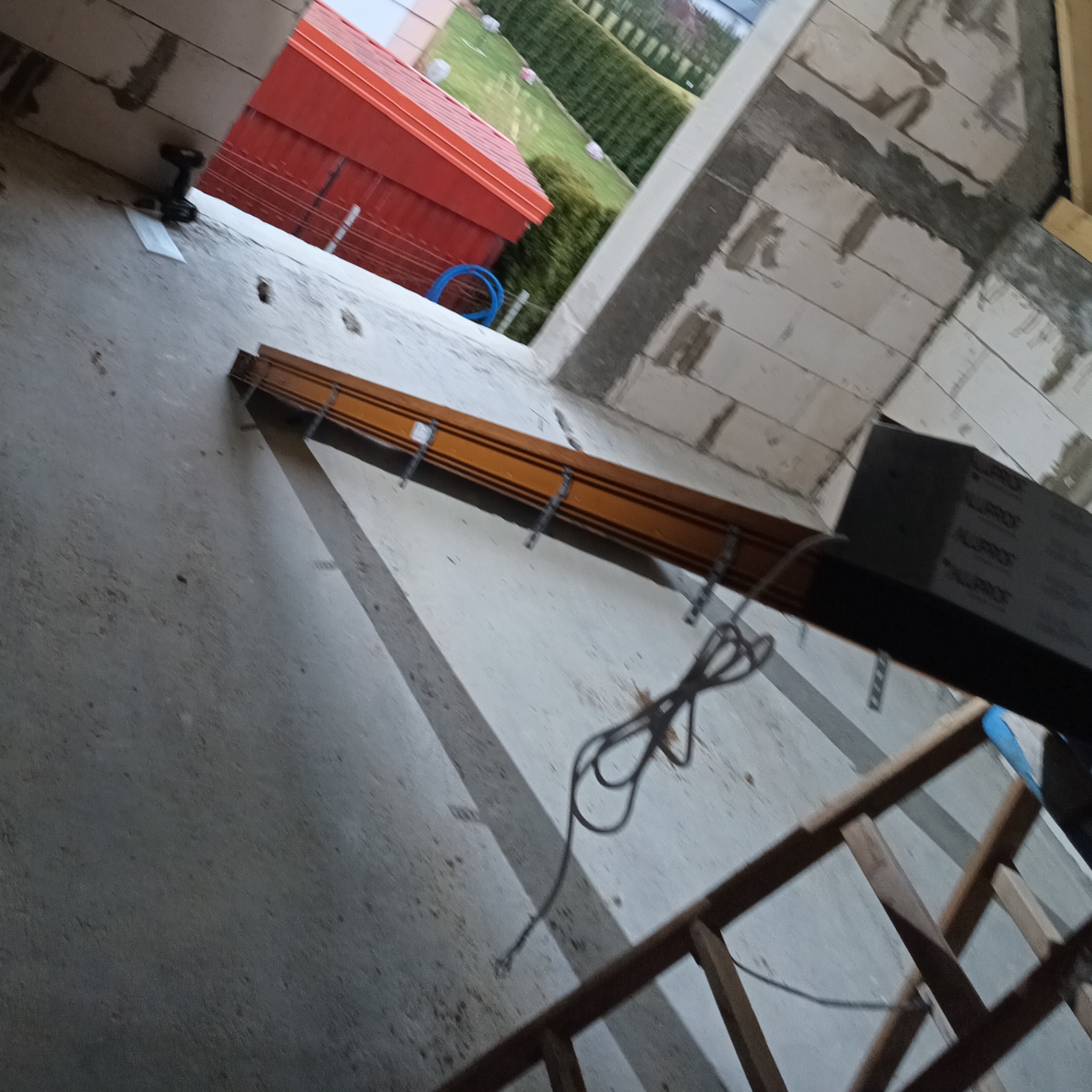 Montaż zewnętrznej rolety okiennej w trakcie prac wykończeniowych, widoczne elementy konstrukcyjne i przewody.