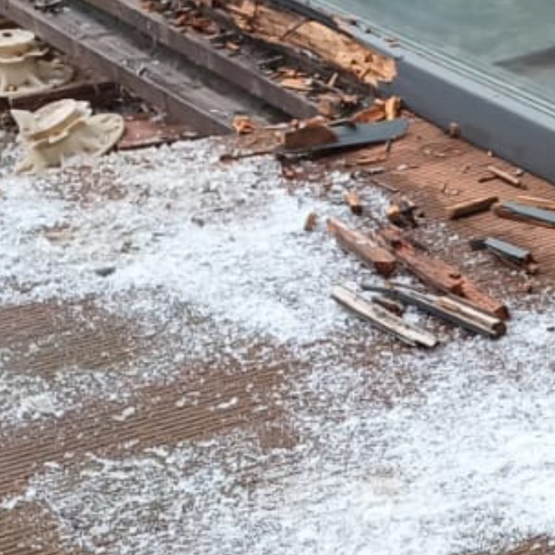 Uszkodzony taras kompozytowy z widocznymi elementami konstrukcyjnymi i białym nalotem przypominającym pleśń lub wykwity. Widoczne fragmenty desek i uszkodzone podłoże tarasu.