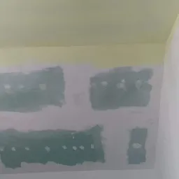 Sufit poddasza w trakcie szpachlowania, widoczne nałożone warstwy gładzi gipsowej i narzędzia malarskie, w tym wałek z długim uchwytem.