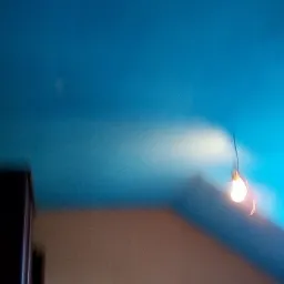 Niedoskonałe ujęcie niebieskiego sufitu z wiszącą żar&oacute;wką i fragmentem drabiny malarskiej, widoczny bok szafy.