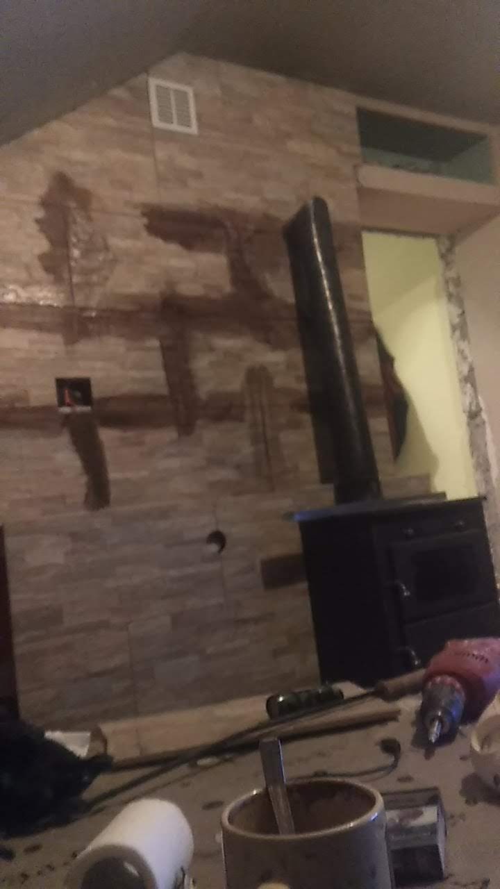 Wyszków: Fragment ściany z imitacji kamienia w trakcie montażu, widoczne ślady kleju, otwór na rurę oraz piec typu koza. W tle widoczne narzędzia.