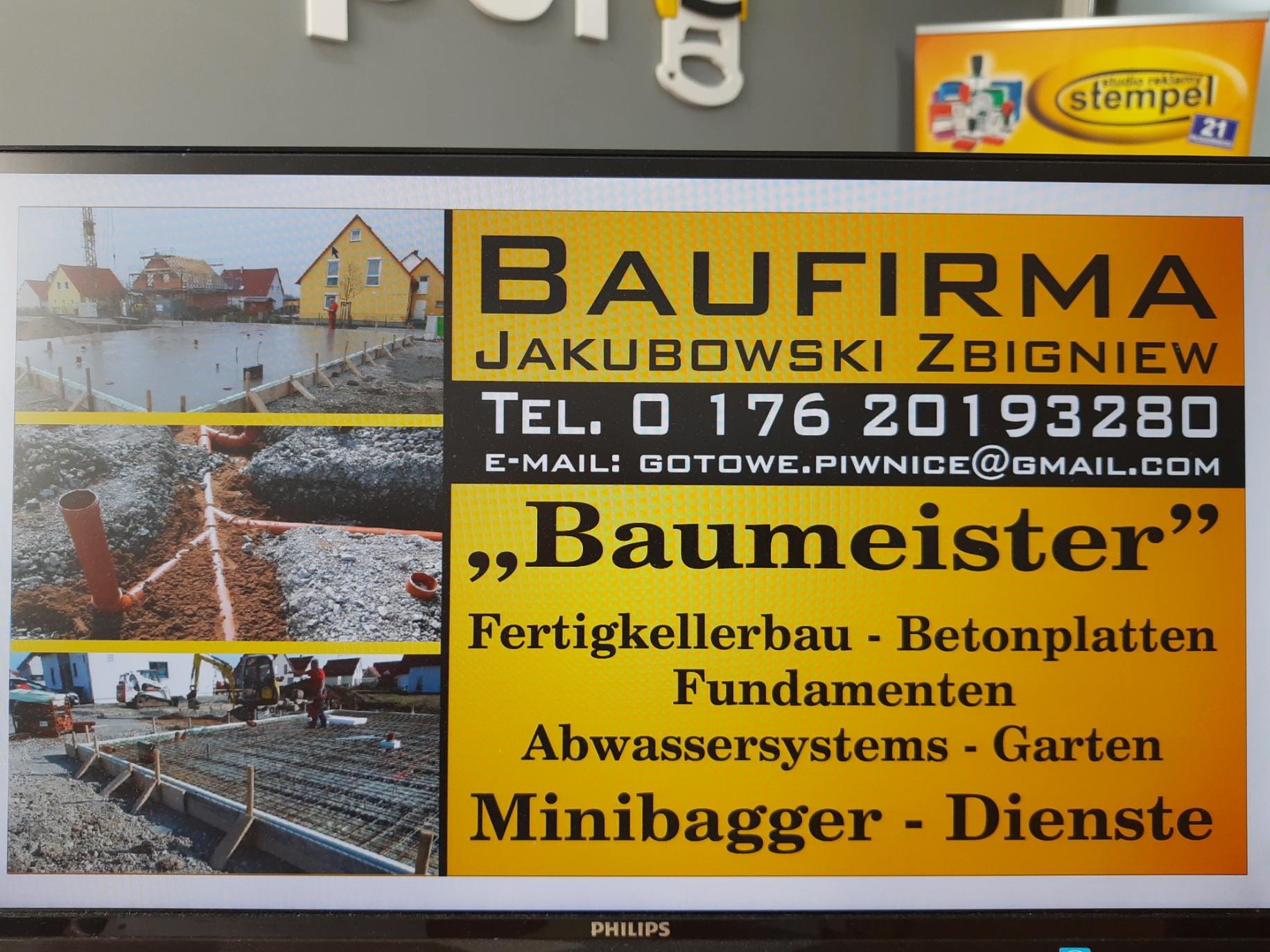 Reklama firmy budowlanej Jakubowski Zbigniew z numerem telefonu i adresem e-mail, prezentująca etapy budowy: wylany fundament, ułożone rury kanalizacyjne i budynek w trakcie wznoszenia.
