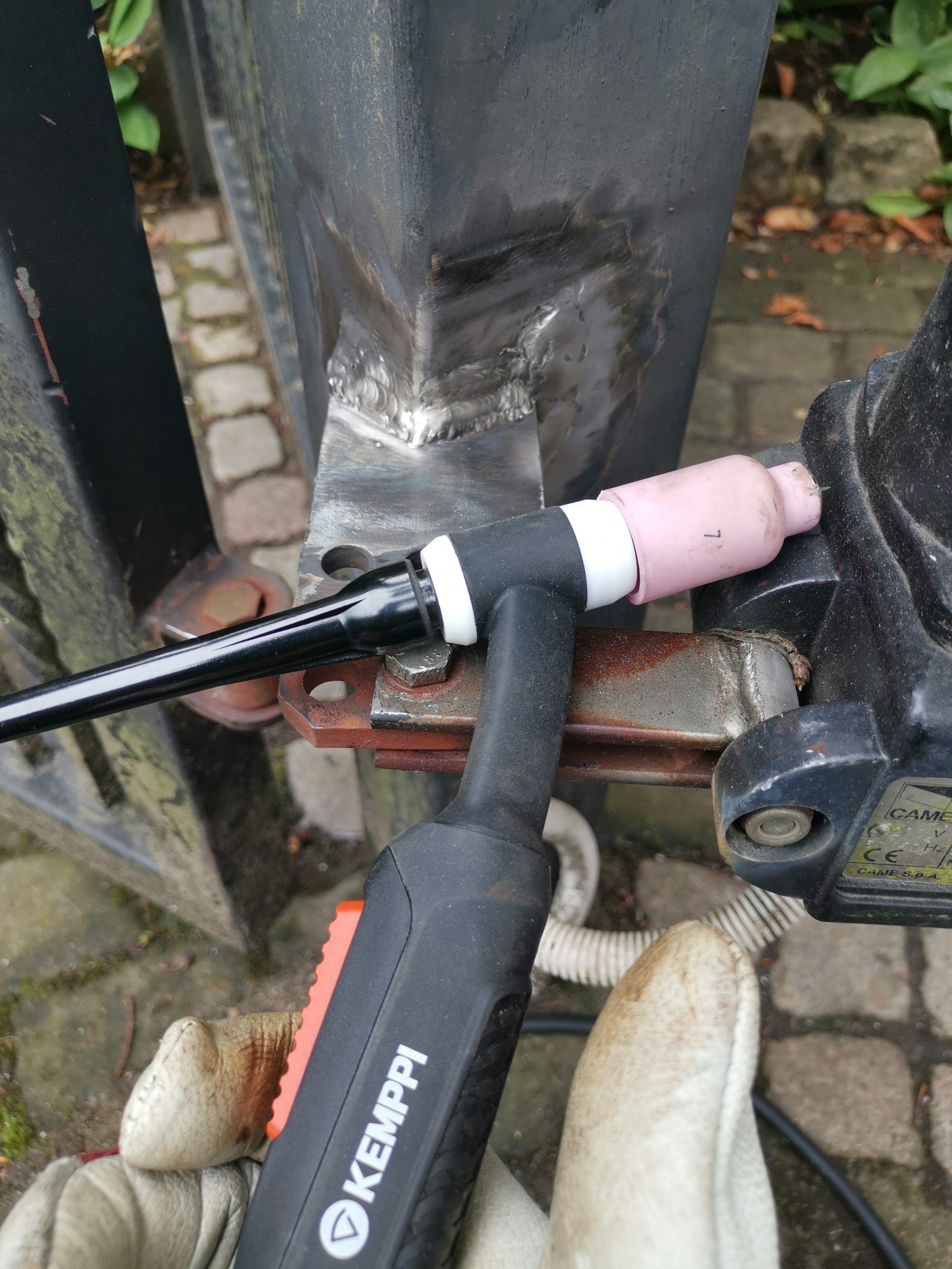 Spoina na metalowej konstrukcji bramy w Gdańsku, wykonana metodą TIG, widoczny uchwyt spawalniczy Kemppi i rękawica ochronna.