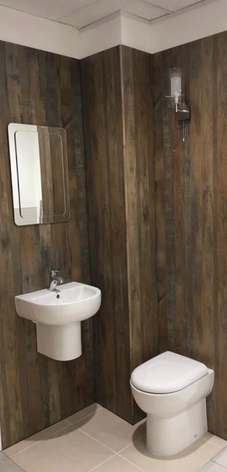 Nowoczesna łazienka z drewnopodobnymi panelami ściennymi, białą ceramiką sanitarną i minimalistycznym lustrem z zaokrąglonymi rogami.