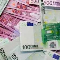 Stos banknotów euro o nominałach 100 i 500, ułożonych chaotycznie na płaskiej powierzchni, z przewagą zielonych i różowych barw.