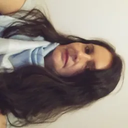 Portret kobiety z długimi, ciemnymi włosami, ubrana w jasnoniebieską bluzkę, sfotografowana z nietypowej perspektywy, z bliska