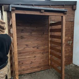 DREWBET SP. Z O.O. - Brązowa drewniana konstrukcja altany w trakcie budowy, z widoczną konstrukcją szkieletową i częściowo zamontowanymi deskami, z bliska, na zewnątrz.