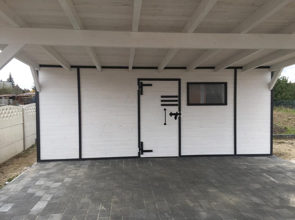 Biała, drewniana altana z czarnymi detalami, widok z zewnątrz. Szara kostka brukowa przed wejściem, ogrodzenie w tle. Minimalistyczny design.