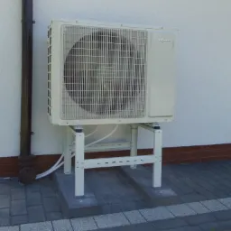 Zewnętrzna jednostka klimatyzacji Viessmann zamontowana na metalowym stelażu przy elewacji budynku z widoczną rurą spustową