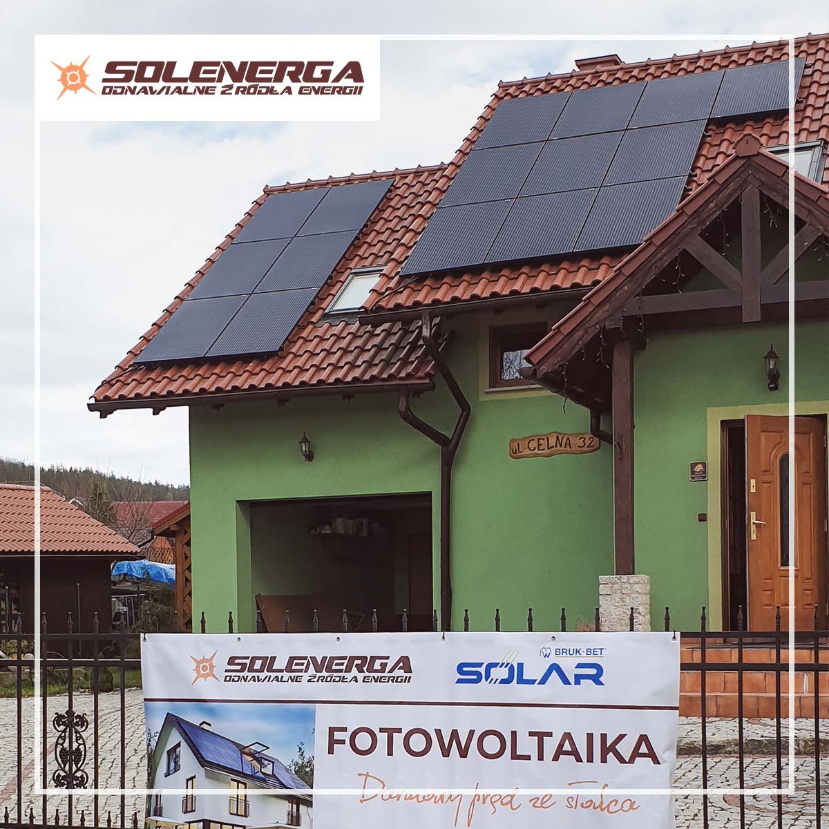 Dom z zieloną elewacją i panelami słonecznymi na dachu z czerwonej dachówki, widoczny baner reklamowy z logo firmy i napisem 'Fotowoltaika. Darmowy prąd ze słońca.'