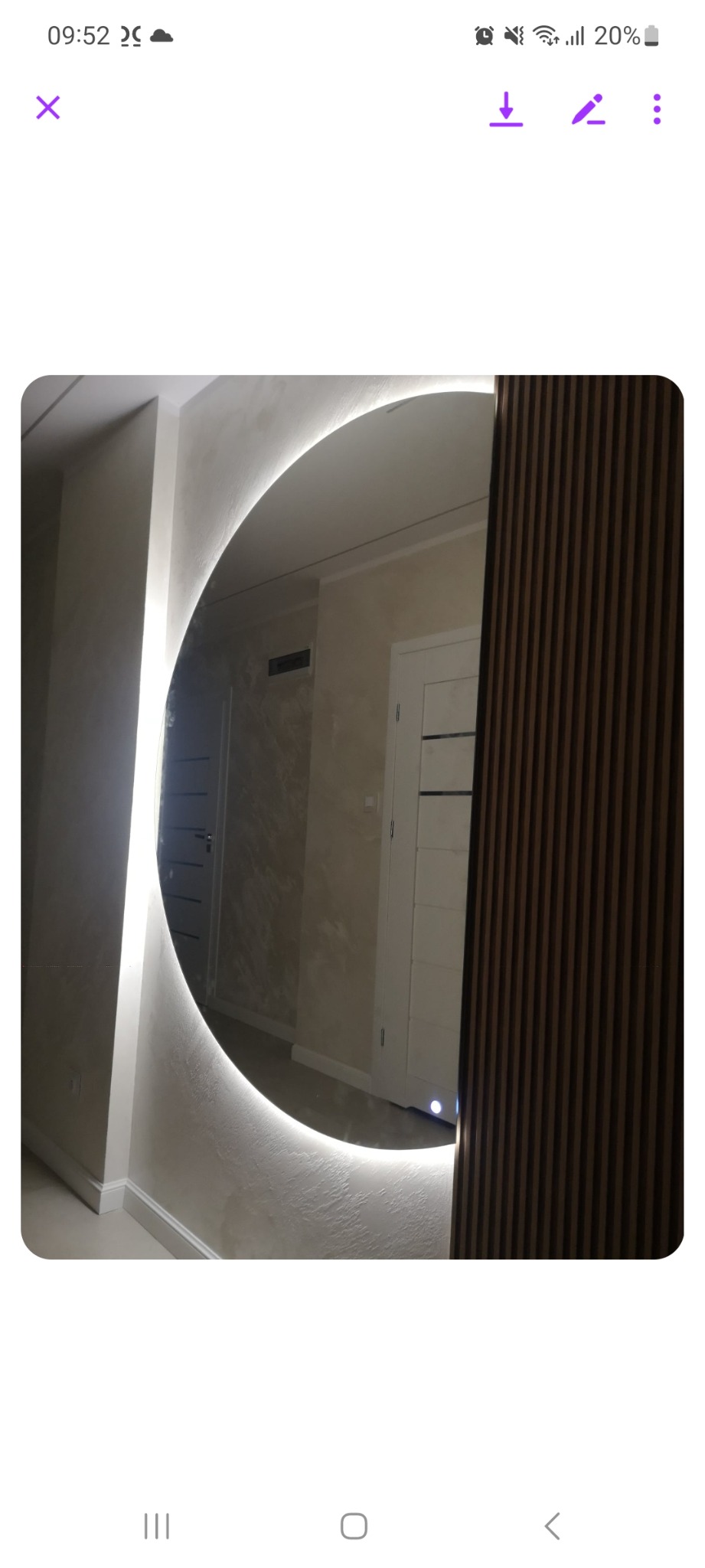 Okrągłe lustro z podświetleniem LED wkomponowane w ścianę z dekoracyjną strukturą, obok panelu ściennego z pionowych listewek.