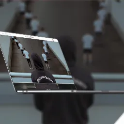 Prezentacja sklepu internetowego Villain na ekranie MacBooka Pro, z widocznym motywem graficznym i osobami w tle, unoszącego się nad rozmytym tłem.