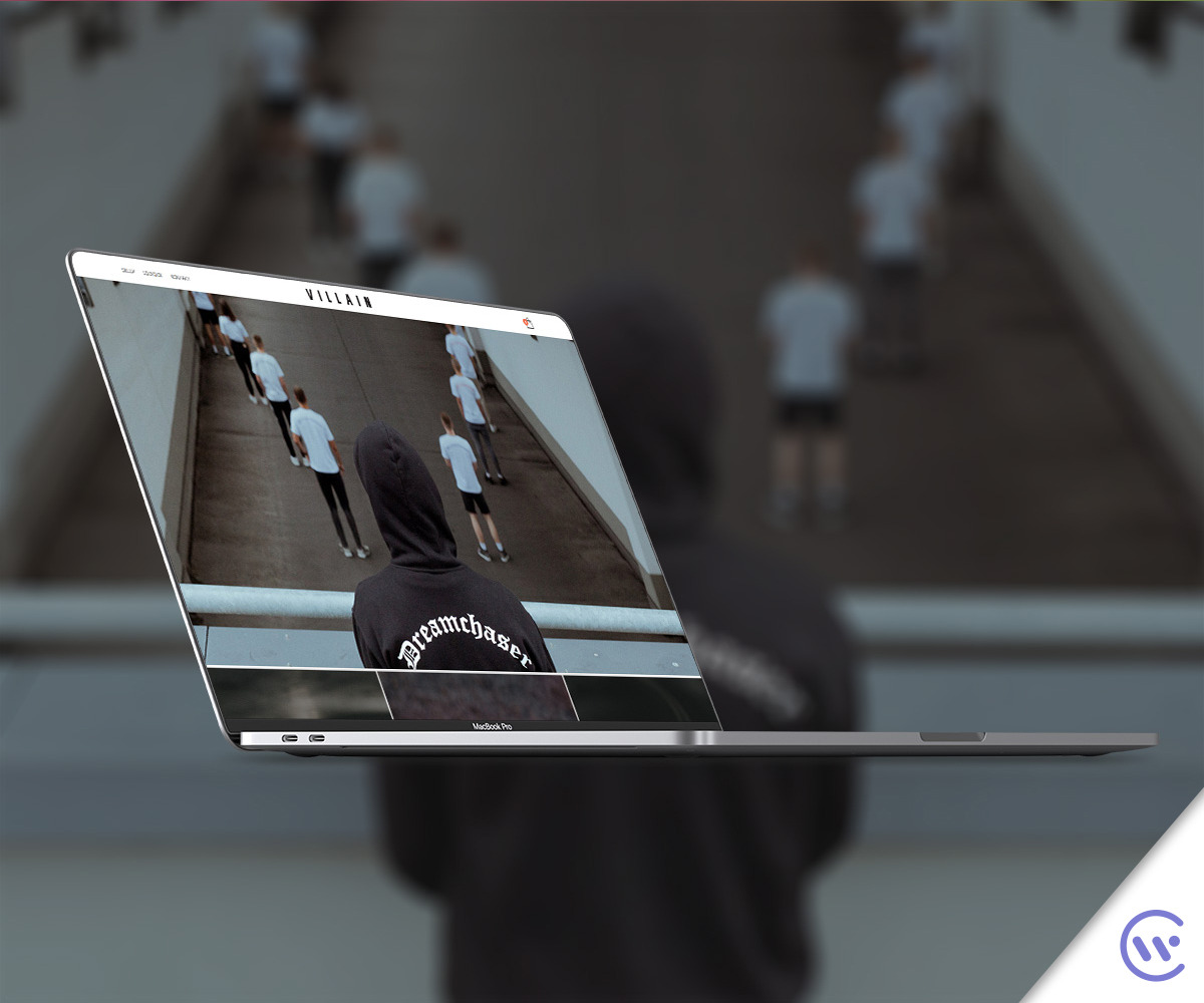 Prezentacja sklepu internetowego Villain na ekranie MacBooka Pro, z widocznym motywem graficznym i osobami w tle, unoszącego się nad rozmytym tłem.