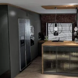 Nowoczesna kuchnia z szarymi szafkami, drewnianym blatem i ścianą z czerwonej cegły, oświetlona wiszącymi lampami z okrągłymi kloszami.