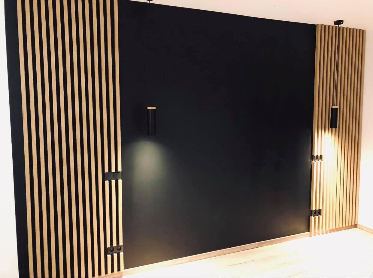 Nowoczesna ściana z czarną farbą i drewnianymi lamelami, z oświetleniem punktowym, minimalistyczny design.