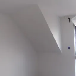 Pomalowane na biało poddasze ze skośnym sufitem i widocznymi puszkami elektrycznymi, świeżo po malowaniu.